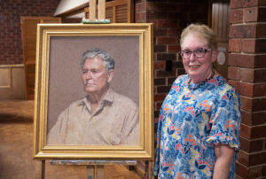 Georgina Halliday with a portrait of her father Pip Comport painted by artist Colin Dudley. 