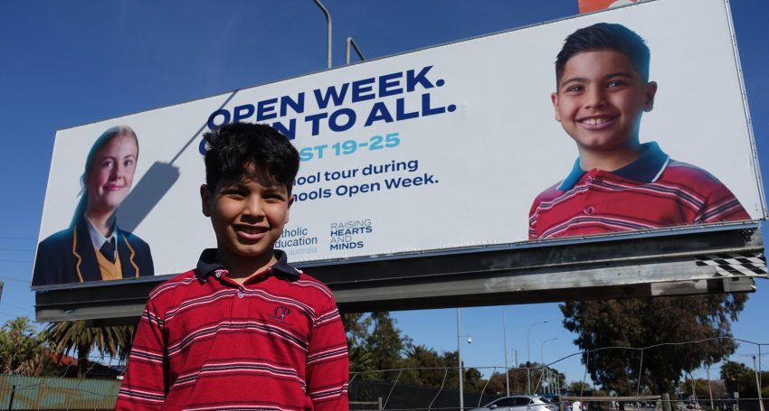 Our Lady Queen of Peace School student Adam with the CESA Open Week billboard on which he is featured.