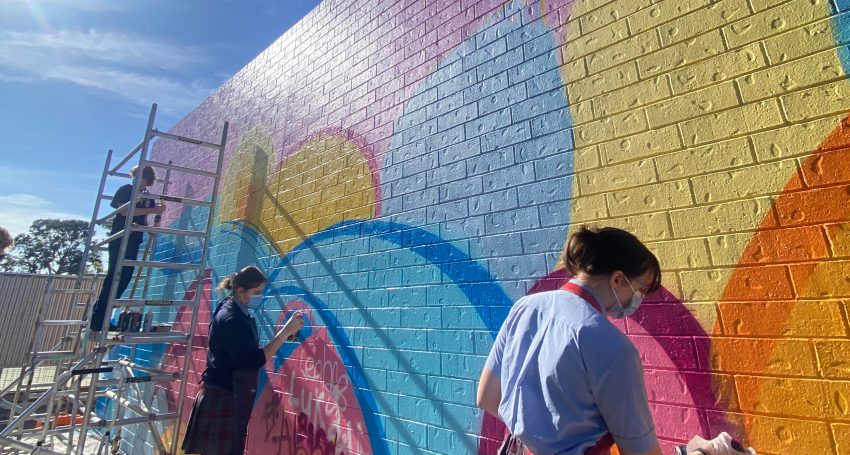 Muralist Leah Grant and Cardijn College students Matthew Ward, Kayla Talbot and Leela Lammin apply a lick of paint to school’s Marian Campus in Noarlunga.